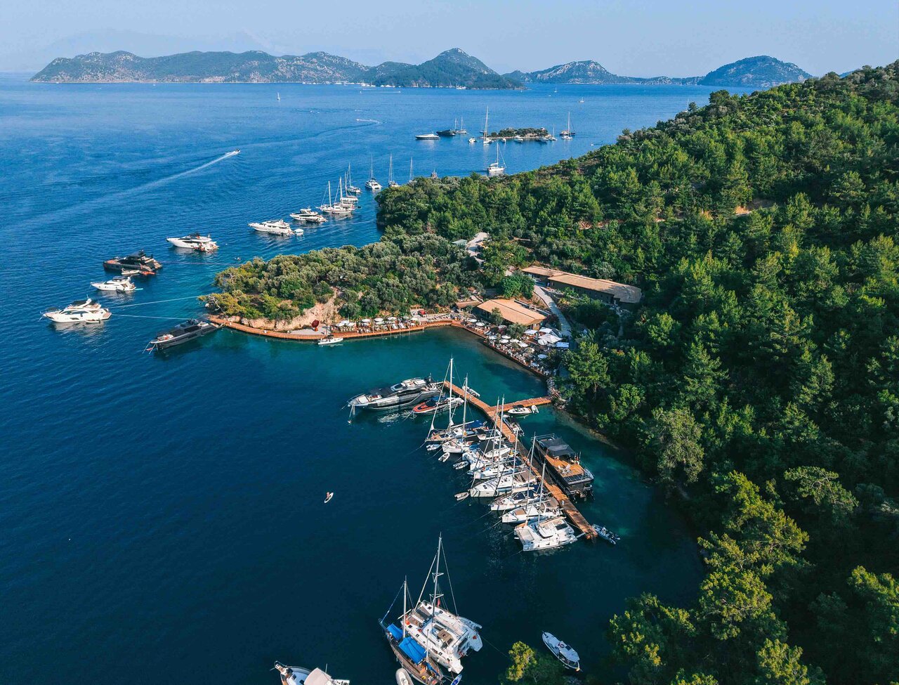 Göcek yat limanı ve yerleşiminin havadan görünümü, arka planda ladin ormanları ve koylar