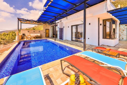 Gece aydınlatmalı havuz ve şezlongların yakın plan çekimi.