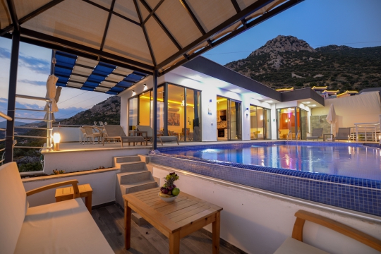 Villa Fıstık 1’in havuz terasında bulunan gölgelikli oturma alanı ve ahşap dış mekan mobilyaları