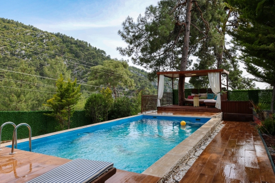 Villa Moby’nin doğa manzaralı özel yüzme havuzu ve havuz başındaki ahşap dinlenme alanı, gözlerden uzak huzurlu bir tatil imkânı sağlamaktadır.