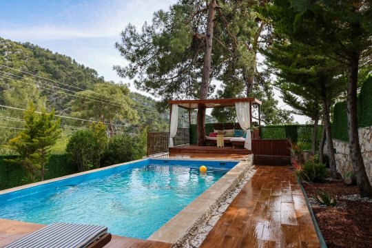 Villa Moby’nin ağaçlar arasında yer alan özel yüzme havuzu ve ahşap dinlenme alanı, doğayla iç içe sakin bir tatil atmosferi sunmaktadır.