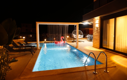 Villa Lacivert 2’nin akşam ışıklandırmalı özel yüzme havuzu ve korunaklı bahçe alanı görünümü.
