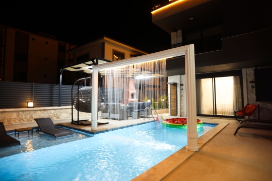 Villa Lacivert’in akşam ışıklandırmalı özel havuzu ve muhafazakar yapısıyla huzurlu tatil imkânı.