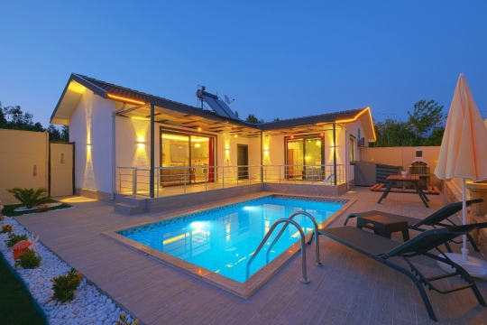 Villa Pra 1’in akşam ışıklarında özel yüzme havuzu ve bahçe alanı