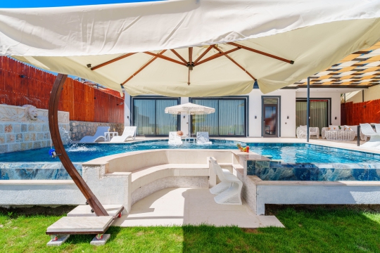 Gölgelikli oturma alanı ve havuz başı konfor sunan lüks villa