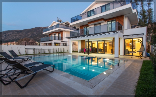 Fethiye Ovacık Villa Twins 17’nin özel havuzu, şezlong alanları ve modern villa mimarisini bir arada gösteren geniş açı dış cephe görünümü.