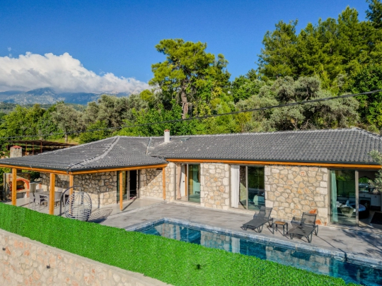 Doğal taş detaylarla tasarlanan villa, modern yaşam alanları ve özel havuzuyla dikkat çekmektedir.