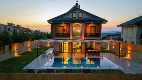 Ovacık'ta yer alan Villa Cozy'nin gün batımında özel havuzu ve şık dış cephesiyle benzersiz tatil deneyimi.
