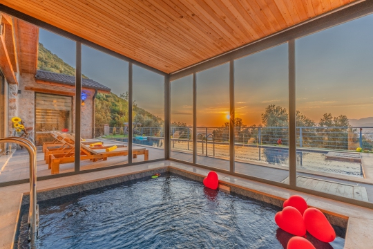 Fethiye Karapınar'daki Villa Montana'nın kapalı havuzu, gün batımı manzarası eşliğinde dört mevsim konforlu bir konaklama deneyimi sunmaktadır.