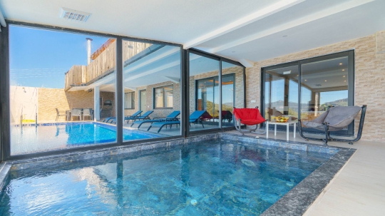Kalkan Ulugöl Villa Sidney 3’ün camlarla çevrili kapalı yüzme havuzu ve modern dinlenme alanı.