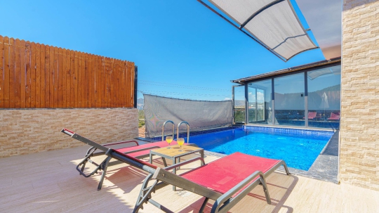 Villa Sidney 4’ün korunaklı özel yüzme havuzu, şezlongları ve gün batımı manzaralı havuz başı dinlenme alanı.