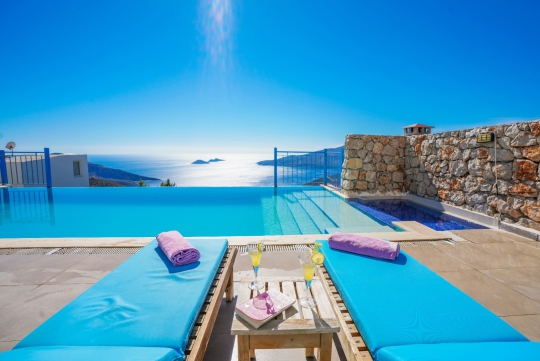 Kalkan Kördere Villa Bonny 1’in eşsiz deniz manzarasına hakim sonsuzluk havuzu, şezlongları ve havuz başı dinlenme alanı.