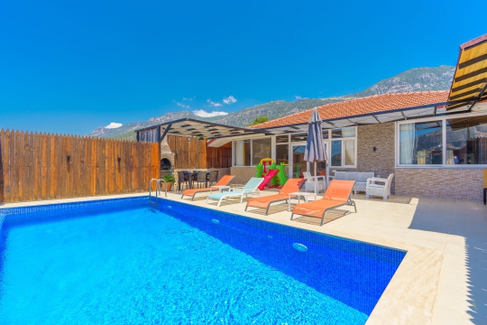Kalkan Villa Sidney 1’in korunaklı özel havuzu, şezlongları ve doğa manzarasına açılan geniş güneşlenme alanı.