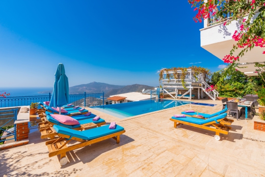 Deniz manzaralı özel havuz, geniş güneşlenme alanı ve renkli şezlonglarıyla sakin ve keyifli bir villa tatili atmosferi sunmaktadır.