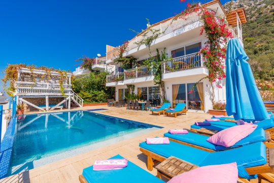 Özel havuzlu villanın modern dış cephesi, geniş havuz terası ve şezlong alanları aileler için ferah bir tatil ortamı sunmaktadır.
