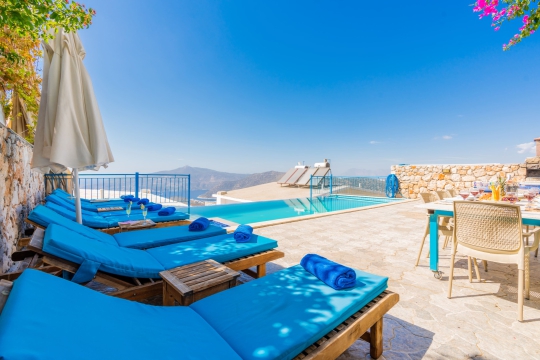 Villa Bonny 2 Kalkan’da panoramik deniz manzaralı sonsuzluk havuzu, şezlongları ve geniş güneşlenme alanı.