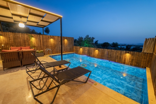 Villa Rua 1’in havuz kenarındaki şezlong ve güneşlenme alanı, Kalkan’da doğa içerisinde dinlenmek ve güneşin tadını çıkarmak için ideal.