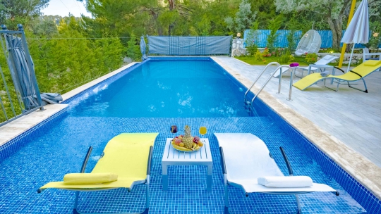 Kalkan Villa Spada’nın 9.5 x 3.5 metre ölçülerindeki özel yüzme havuzu, geniş havuz terası ve şezlong alanından görünüm.
