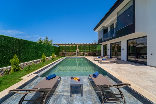 kiralık villa bahçesinde geniş yüzme havuzu, şezlong alanı ve doğa manzarası