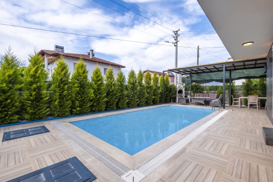 Çisem 3 Villa’nın korunaklı özel yüzme havuzu, geniş güneşlenme alanı ve huzurlu bahçe manzarası.
