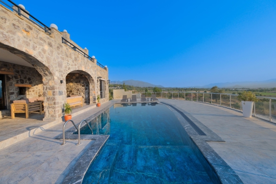 Villa Palace'ın sonsuzluk hissi veren özel havuzu ve taş mimarisiyle doğa manzaralı dış alanı.