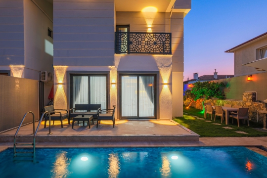 Villa Linda 1'in akşam aydınlatmalı özel havuzu ve şık bahçe alanı.