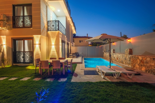 Villa Linda 2'nin akşam aydınlatmalı özel havuzu ve bahçe alanı.