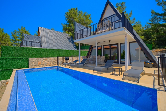 Villa Mino Duo'nun geniş özel yüzme havuzu, güneşlenme alanı ve doğayla iç içe konumuyla huzurlu villa tatili sunan dış cephesi.