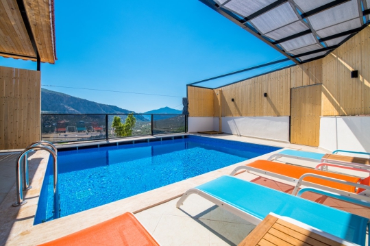 Kalkan Ulugöl Villa Sidney 2’nin özel havuzu, renkli şezlongları ve panoramik doğa manzaralı güneşlenme alanı.