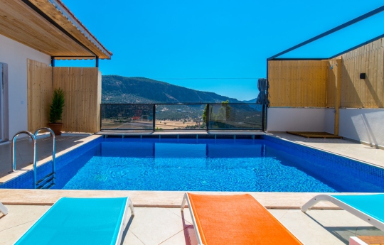 Kalkan Villa Sidney 2’nin doğa ve dağ manzarasına açılan korunaklı özel havuzu ve havuz başı güneşlenme alanı.