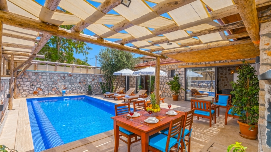 Gölgelikli ahşap pergola altında hazırlanan şık dış mekân yemek masası takımı.