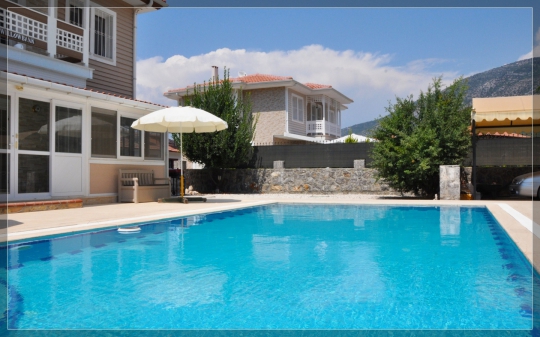 Villa Twins 15’in berrak özel yüzme havuzu, taş duvarlarla çevrili bahçesi ve Ovacık’ın doğal manzarası.