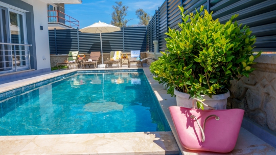 Villa Akros'un geniş özel havuzu, güneşlenme alanı ve korunaklı bahçesiyle huzurlu tatil keyfi.