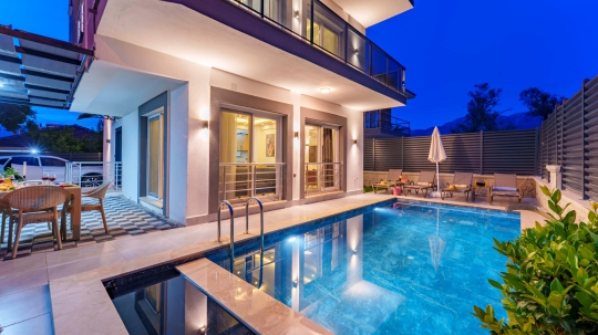 Villa Akros'un akşam ışıklandırmalarıyla öne çıkan özel havuzu ve modern villa mimarisi.