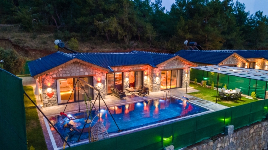 Villa New Star 1'in gece manzarasında ışıklandırılmış özel havuzu ve modern taş villa tasarımı.