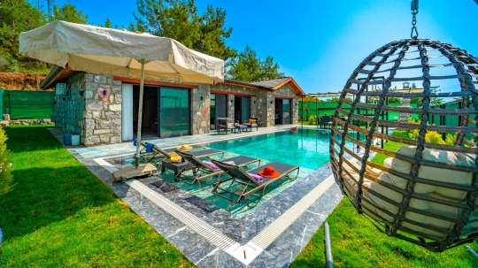 Villa Nimo Duo'nun korunaklı havuzu, bahçe oturma alanı ve modern taş mimarisi aile tatilleri için ideal bir ortam sunmaktadır.