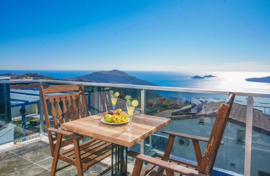 Kalkan Kördere Villa New Porto’nun balkonundan panoramik deniz ve doğa manzarası eşliğinde keyifli yemek ve dinlenme alanı.