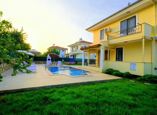 Villa Beta’nın geniş yeşil bahçesi, korunaklı özel havuzu ve dubleks villa mimarisiyle huzurlu dış alan görünümü.