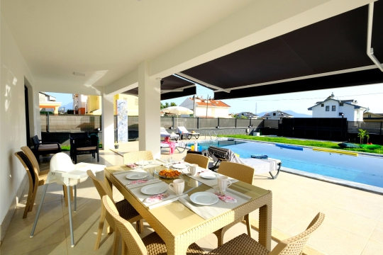 Fethiye Çiftlik Villa Varoni’nin havuz manzaralı terası, açık hava yemek masası ve geniş ailelere uygun dinlenme alanı.