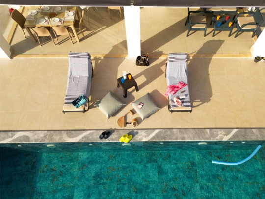 Fethiye Villa Varoni’nin özel yüzme havuzu, şezlongları ve havuz başı güneşlenme alanının üstten görünümü.