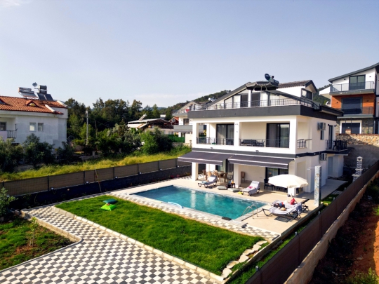 Villa Varoni’nin geniş bahçesi, özel yüzme havuzu ve modern dubleks dış cephesiyle ferah dış yaşam alanı.