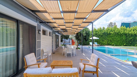 Gölgelikli veranda ve havuz başı oturma alanı ile villa avlu 