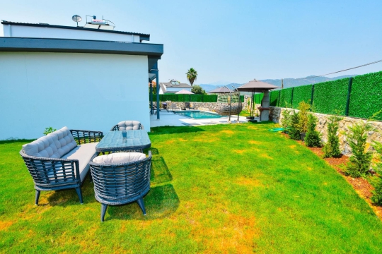 Geniş yeşil bahçede oturma alanı ve dinlenme köşesi ile villa avlu
