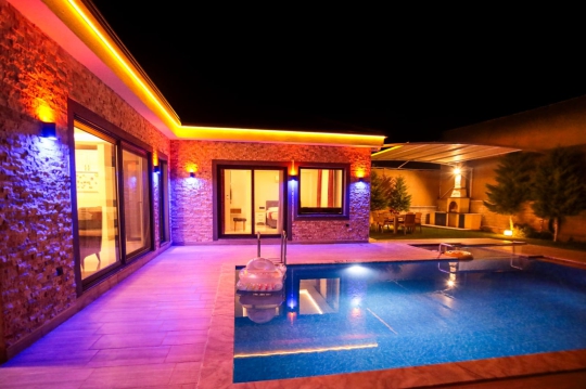 Villa Sole 2’nin gece aydınlatmalı korunaklı havuzu ve jakuzili lüks tatil alanı görünümü.