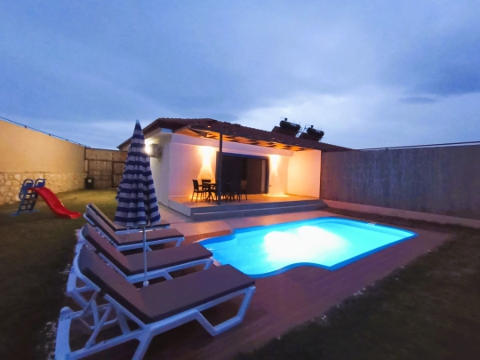 Villa Elmas 2’nin gece aydınlatmalı özel yüzme havuzu ve modern mimarisiyle keyifli villa tatili deneyimi.