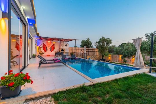 Villa Tawny 1’in akşam ışıklandırmalı özel havuzu ve modern dış tasarımıyla muhafazakar villa konsepti.