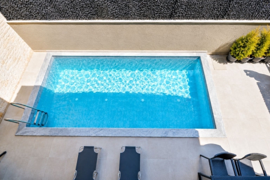 Özel yüzme havuzunun üst açıdan görünümü – Korunaklı ve konforlu yapısıyla ailelere uygun kiralık villa deneyimi.