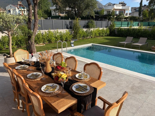 Fethiye Ovacık’ta bulunan Villa Aura 2’nin havuz başında konumlanan şık yemek masası ve geniş yaşam alanları.