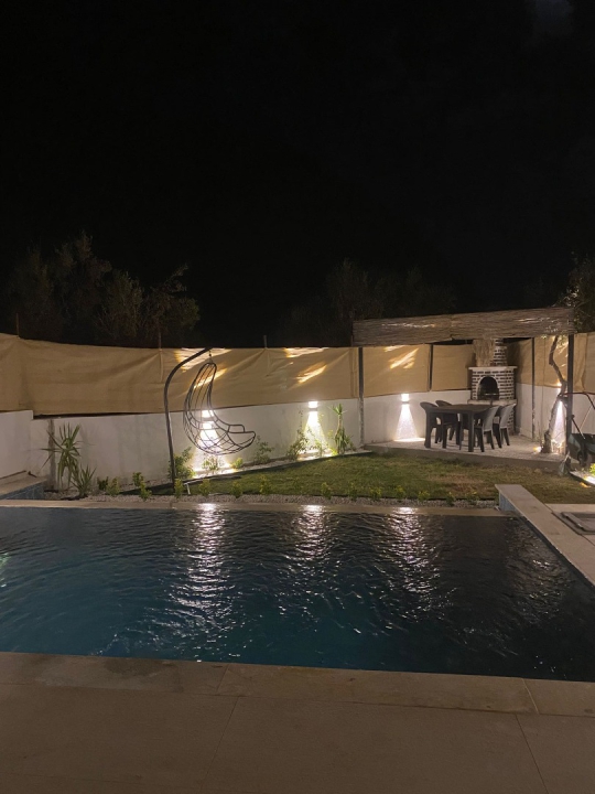 Fethiye Faralya’da doğa manzaralı özel havuzlu Villa Derina’nın akşam aydınlatmalı havuz alanı.