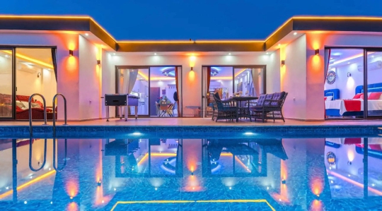 Kalkan Palamut Köyü’nde bulunan Villa Leman’ın akşam aydınlatmalı özel havuzu ve modern mimarisiyle dikkat çeken lüks dış cephesi.